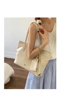 Detail of cream leather tote bag with matching hanging coin purse and embossed logo