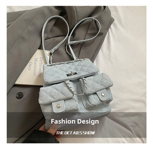 Detailed shot of quilted denim backpack featuring silver chain straps and turn-lock closure