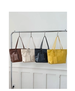 Row of large PU leather tote bags in four colors featuring knot handles and mini pouches