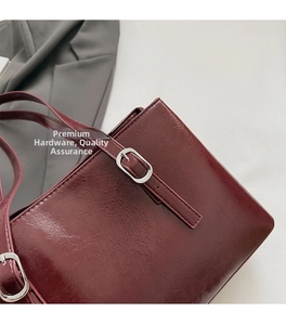 Detail of burgundy tote bag with textured faux leather and silver square buckle strap