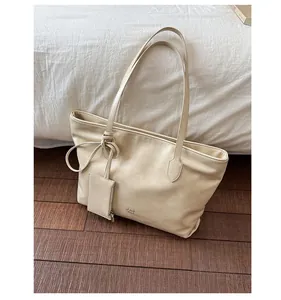 Detail of cream beige leather tote bag with a bow knot strap and a small card holder charm