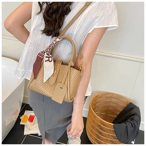 Sac seau tissé tendance avec détail de foulard porté par un mannequin dans un décor doux