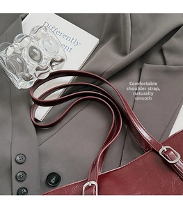 Close-up of wine red tote bag with adjustable thin straps and silver metallic buckles