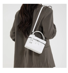 Detail of white croco-embossed vanity bag with smooth double zipper and top handle
