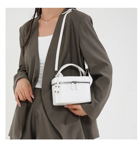 Detailed close-up of white crocodile pattern texture and silver rivet hardware on the handbag