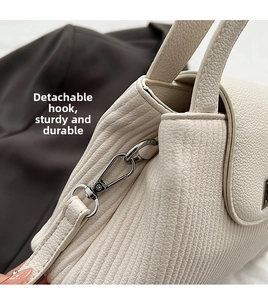 Dettaglio del moschettone in metallo argento e pelle martellata di borsa beige