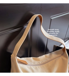 Dettaglio della tracolla larga in tela e della zip in metallo sulla borsa beige
