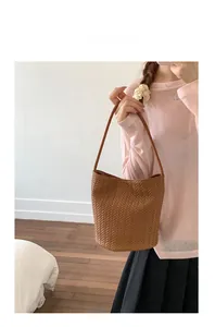 Detail of hand-woven brown leather texture and V-pattern on luxury bucket tote bag