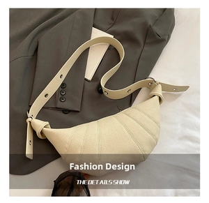 Detail of beige crescent crossbody bag with lychee texture and metal eyelet wide strap