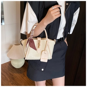 Detailed view of woven texture and golden clasp on beige bucket bag with decorative scarf