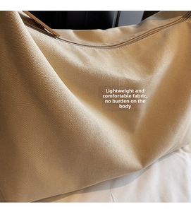 Dettaglio del tessuto di tela beige spessa e della tracolla in pelle marrone scuro della borsa