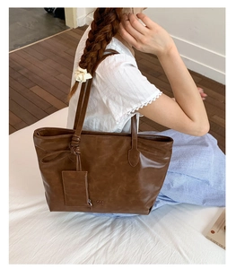 Detail view of large brown soft leather tote bag with logo embossing and matching pouch