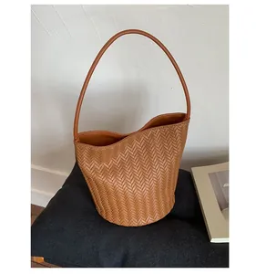Detailed view of brown woven leather texture on a stylish bucket shoulder bag for women