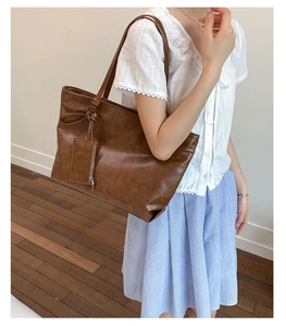 Close-up of brown PU leather tote bag featuring a textured surface and small card pouch accessory