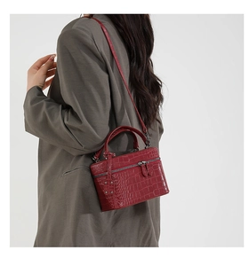 Detailed macro view of red crocodile pattern leather on a compact square box handbag