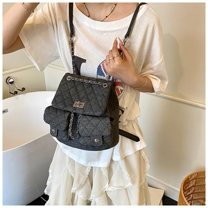 Detail of quilted dark grey backpack with silver chain straps and metallic lock closure