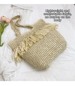 Close-up of beige straw tote bag featuring dense tassel fringe and fine woven texture
