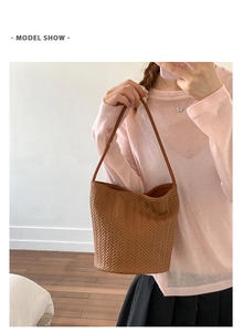 Close-up of brown woven leather bucket bag with dense V-shaped texture and thin strap