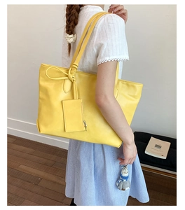 Detail of large yellow leather tote bag with matching lanyard pouch for daily commute