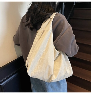 Detailed view of cream nylon tote bag showing soft pleated texture and zipper