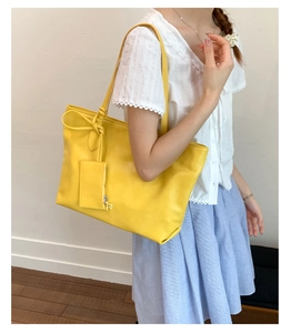 Detail of a bright yellow PU tote bag with a matching small zipper pouch and slim straps