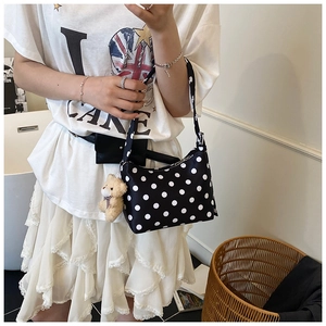 Close-up of black and white polka dot shoulder bag with a brown teddy bear pendant