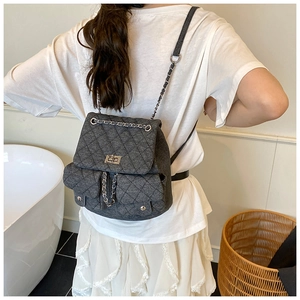 Detail of grey quilted tweed backpack with silver chain straps and metallic twist lock