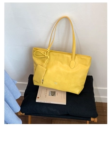 Detail of yellow soft leather tote bag featuring gold PAN TOR logo and mini side pouch