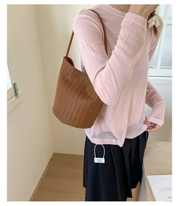 Detail of dark brown woven tote bag on shoulder, showcasing the texture and large capacity