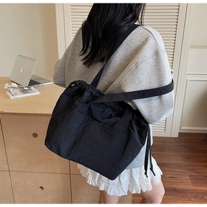 Detail of black nylon drawstring tote bag with side pockets for daily casual use