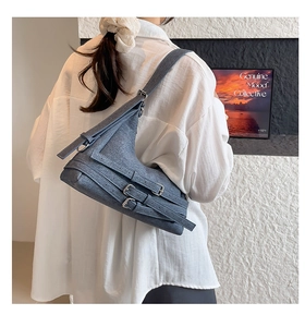 Détail du sac croissant gris-bleu avec brides à boucles multiples sur cuir texturé