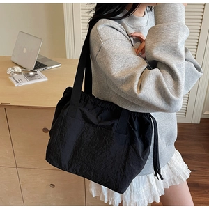 Detailed side view of a large black nylon tote bag with drawstring closure and wide strap