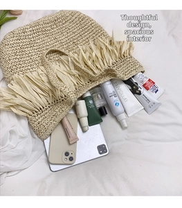 Detail view of the spacious straw tote bag interior holding a tablet and cosmetics