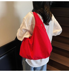 Lifestyle view of a large red tote bag styled with white shirt on wooden stairs