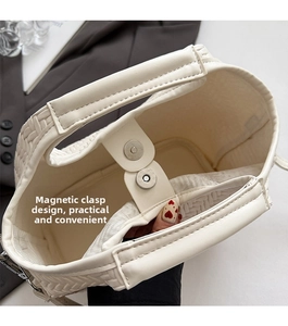 Detail view of white woven bucket bag featuring a secure magnetic closure and neat lining