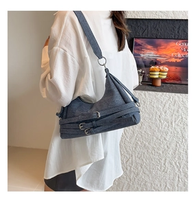 Détail du sac croissant en denim bleu avec boucles argentées et large bandoulière