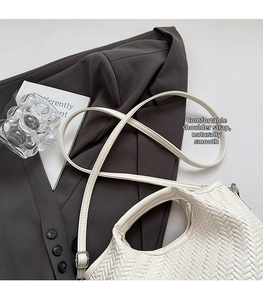 Detail of white woven texture on crossbody bag placed on a grey blazer suit