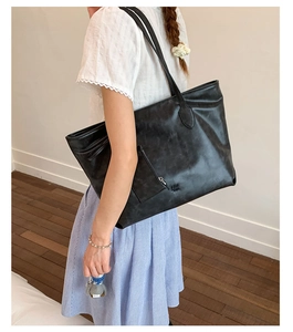 Detail of matte black leather tote bag with embossed PAR TGR logo and side zipper pocket