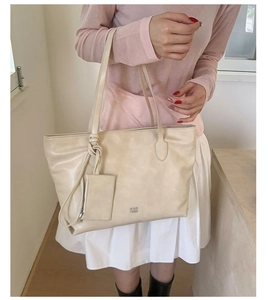 Detail of cream leather tote bag with PAN TOR logo and matching small zipper pouch