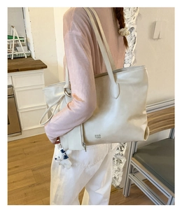 Detail view of large cream tote bag with bear charm and matching coin purse accessory