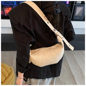 Detail of adjustable strap and lychee grain leather texture on off-white dumpling bag