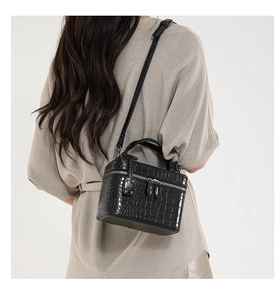 Rear view of a model wearing a black crocodile pattern crossbody bag with silver zippers