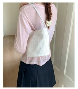 White woven bucket bag on shoulder showing detailed texture and minimalist Korean design
