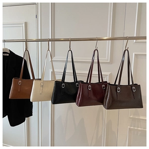 Detailed close-up of five colorful minimalist faux leather tote bags hanging on a rack