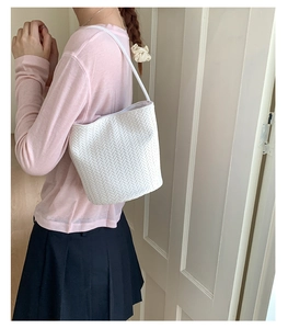 White woven bucket bag worn by model, showing texture and versatile shoulder strap style