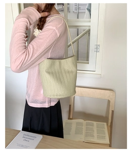 French vintage off-white woven bucket bag shown on a model with minimalist shoulder strap