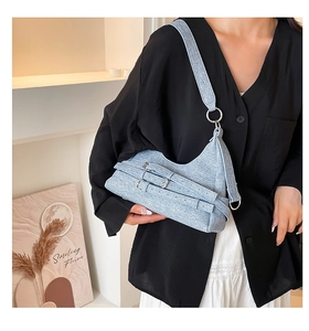 Gros plan du sac croissant bleu clair avec tissu en denim texturé et boucles argentées