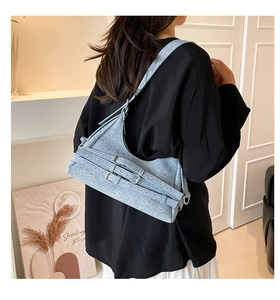 Modèle portant un sac sous le bras en denim bleu clair avec boucles métalliques