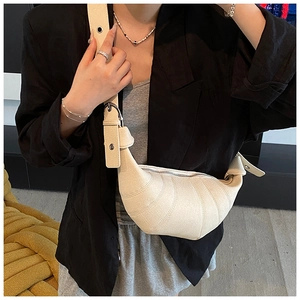 Detail of cream crescent bag with segmented stitching and adjustable wide shoulder strap