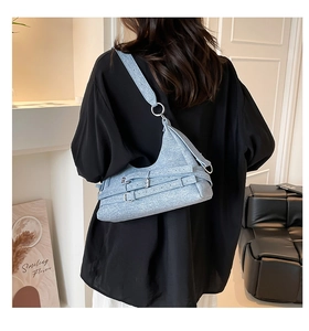 Détail du sac croissant en denim bleu clair avec boucles argentées et large bandoulière